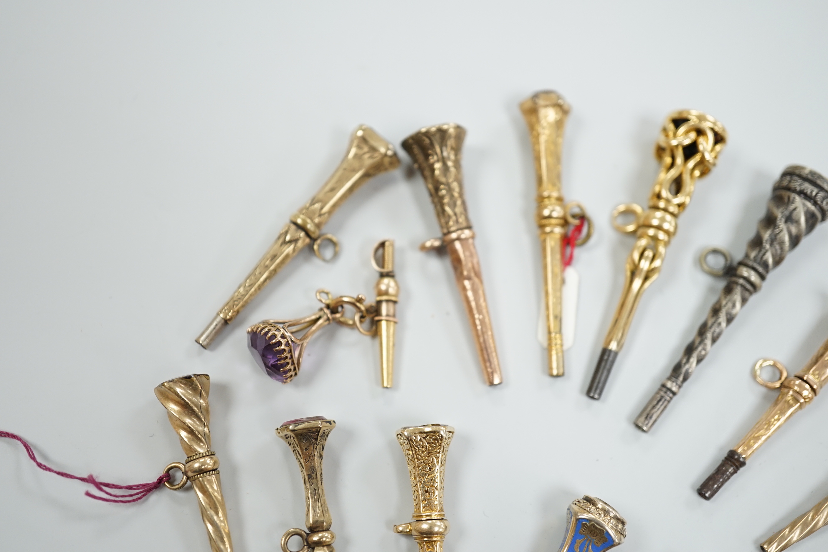 Fifteen assorted 19th century mainly yellow metal overlaid and gem set watch keys, including bloodstone, citrine and white chalcedony and one with enamel, mostly of trumpet form, largest 51mm.
